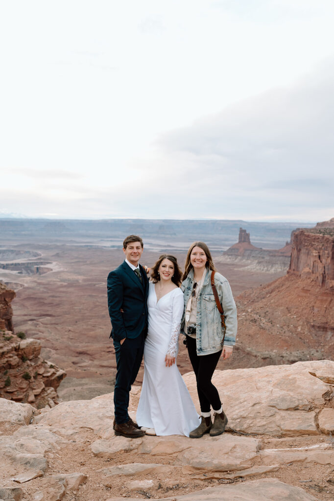 A couple poses with Reagan from Regan Taylor Photography, their Utah elopement photographer. 