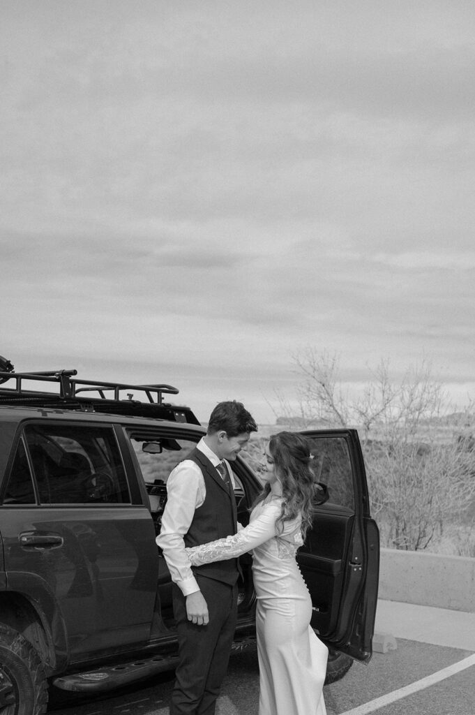 A Moab elopement couple gets ready for their desert elopement in Arches National Park near a 4x4 vehicle. 