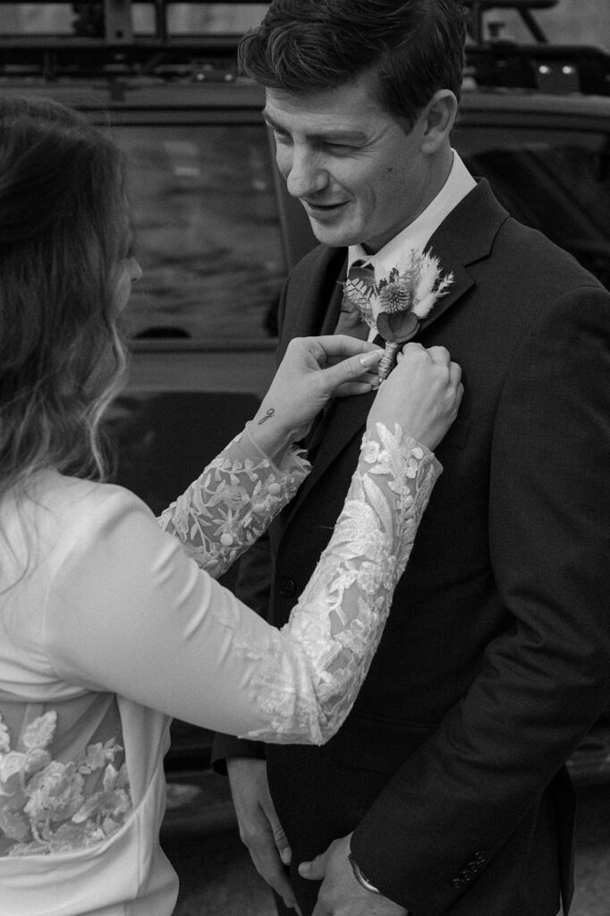 A bride adjusts her groom's dried  boutonniere during their Utah elopement. 